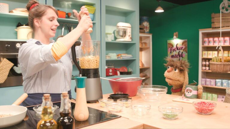 Maya breitet Hummus vor und Moppi beobachtet sie dabei